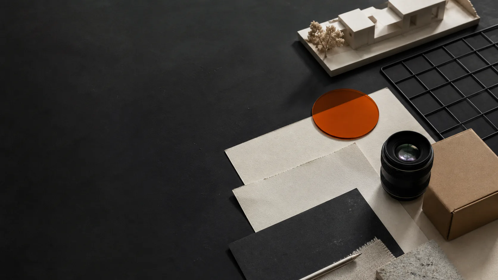 Creative production tools and an architectural model arranged on a dark studio table
